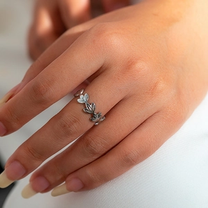 Close-up van een verstelbare zilveren titanium stalen ring met bladmotief aan de hand