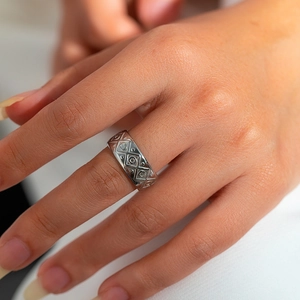 Detailopname van een zilveren ring met geometrisch gegraveerde diamant en cirkelpatronen
