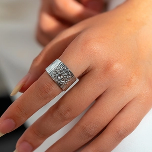 Detail van zilveren stalen ring met reliëf van boze oog en geborstelde textuur