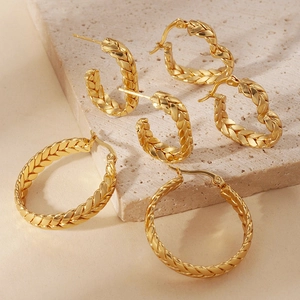 Three pairs of gold-plated stainless steel wheat-pattern heart and hoop earrings on stone