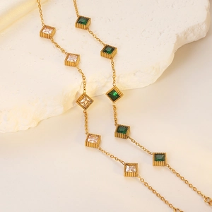 Detail of gold-plated bracelet featuring emerald and white square-cut crystals