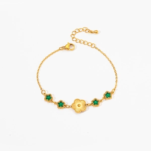 Detail of gold-plated bracelet with emerald star-shaped charms and a floral centerpiece