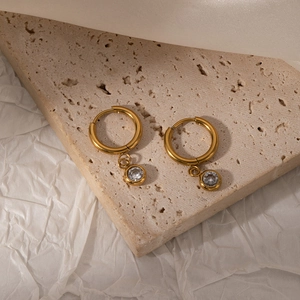 Close-up of gold stainless steel hoop earrings with sparkling clear zircon charms