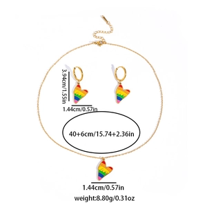 Detailed view of rainbow heart pendant necklace and hoop earrings set in gold finish