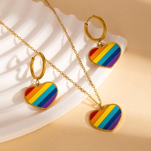 Detail of gold-plated rainbow heart pendant necklace and earrings set on stone