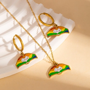 Macro detail of rainbow enamel love pendant and hoop earrings set in polished gold finish