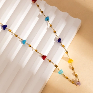 Colorful gemstone bead necklace with gold cube charms and triangular stones on white board