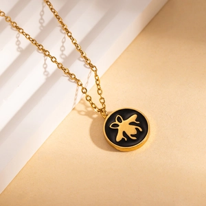 Primo piano della collana con ciondolo ape dorata su espositore bianco testurizzato
