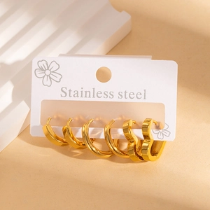 Three pairs of polished gold stainless steel hoop earrings on a display card