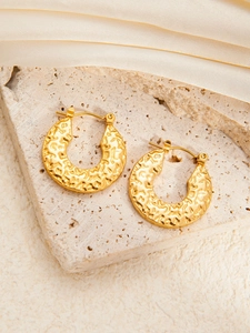 Hammered gold C-shaped hoop earrings with vintage texture on a silk background