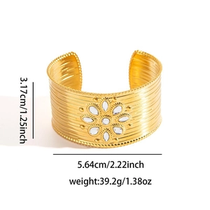 Dettaglio del bracciale rigido dorato con intarsio solare e superficie strutturata