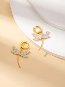 Detailed shot of gold dragonfly earrings featuring white enamel and crystal inlay
