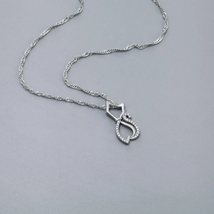 Vue détaillée du pendentif chat évidé en argent avec des strass brillants sur chaîne