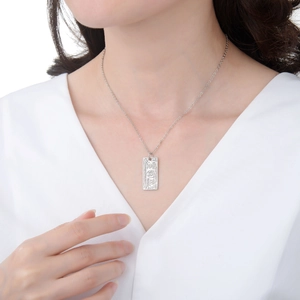 Detailed close-up of a silver dollar bill pendant featuring embossed dollar patterns
