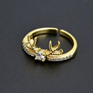 Vue macro d'une bague renne dorée ajustable avec pierres CZ sur un fond gris foncé