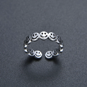 Retro Thai silver open ring featuring continuous smiley face patterns on dark sand background