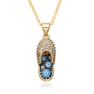 Macro detail of gold slipper pendant with evil eye charms and sparkling zircon inlay