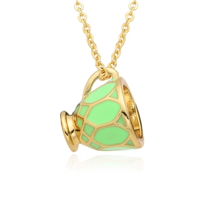 Détail macro du pendentif théière doré avec émail vert et texture en nid d'abeille
