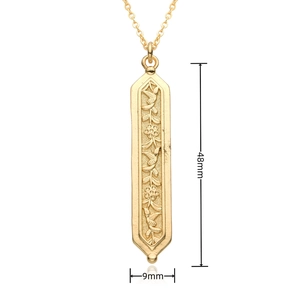 Détail du motif floral et oiseau en relief sur pendentif doré, taille 48mm par 9mm