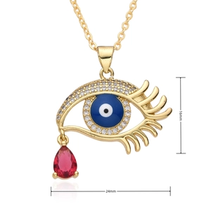 Vue macro d'un pendentif Evil Eye doré avec pierre bleue et gemme rouge 16x24mm