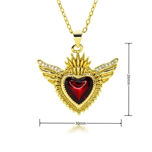 Detail view of a 26x30mm red heart pendant with gold angel wings and radiant crown design