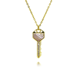 Macro shot of gold key pendant with pink mother-of-pearl inlay and zircon stones