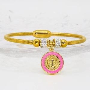 Detail of gold snake chain bracelet with pink enamel religious saint charm and magnet clasp