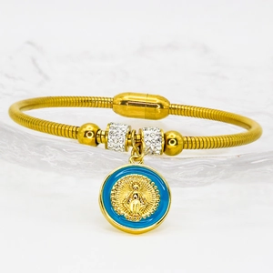 Nahaufnahme des goldenen religiösen Armbands mit blauem Emaille-Anhänger und Magnetverschluss
