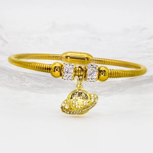 Gros plan d'un bracelet maille serpent dorée avec charmes en zircon et pendentif planète