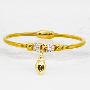 Detailed macro view of a gold shell pendant on a crystal-set snake chain bracelet