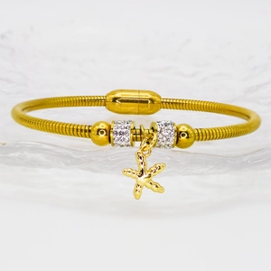 Detail of gold snake chain bracelet featuring crystal beads and a starfish charm