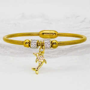 Macro detail of gold snake chain bracelet with sparkling crystal dolphin charm and magnetic clasp