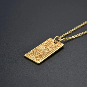 Macro detail of gold hip hop pendant necklace with engraved 100 dollar bill motif