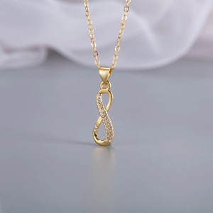 Detailaufnahme der goldenen Infinity-Halskette mit funkelnden Kristallsteinen