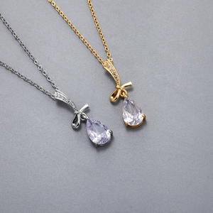 Dettaglio delle collane con fiocco in oro e argento con pendenti in zirconia viola a goccia