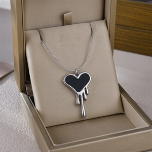 Close-up of a silver liquid lava heart pendant with black enamel inlay on silk lining