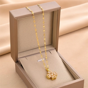 Golden rotating clover necklace with micro-pave crystals in a premium brown jewelry box