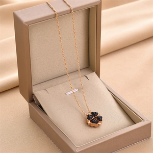 Close-up of four-leaf clover pendant in rose gold with black heart stones in gift box