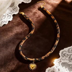 Detail von Leoparden-Stoffband mit goldenem Herzanhänger und verstellbarer Verlängerungskette