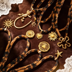 Detail von Leopardenmuster-Stoffhalsketten mit goldenen Anhängern auf Samt