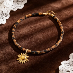 Detailaufnahme von Leoparden-Choker aus Stoff mit glänzendem goldenem Sonnenanhänger