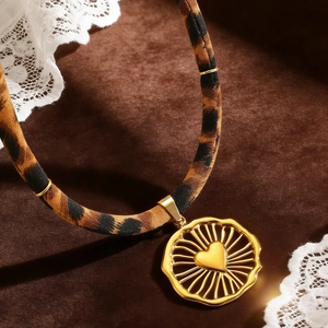 Detail eines Stoffbands mit Leopardenmuster und goldenem Herzanhänger auf Samt