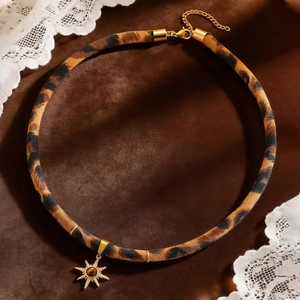Nahaufnahme eines Leoparden-Chokers mit goldenem Sternanhänger und Tigerauge-Stein