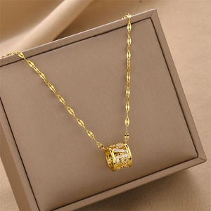 Collier en acier titane doré avec pendentif cylindrique incrusté de cristaux sur un écrin
