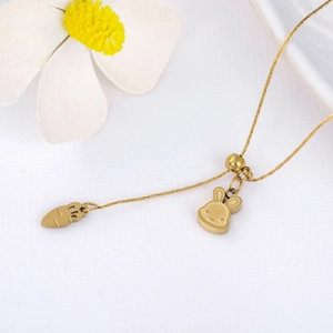 Macro shot of polished gold bunny and carrot charms on a delicate stainless steel chain
