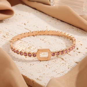 Rose gold honeycomb bangle with pink zircons on a white stone and silk fabric background