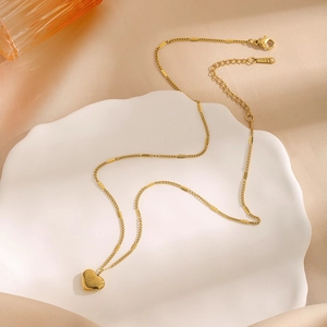 Golden stainless steel necklace with heart pendant and Love engraving on a white plate