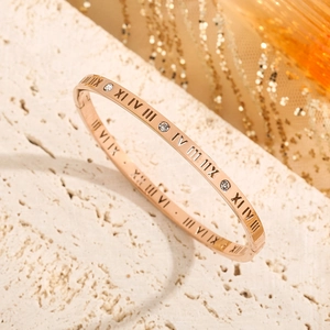 Rose gold roman numeral bangle with inlaid crystals on a minimalist textured stone
