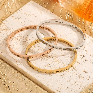Detail of Roman numeral engravings and inlaid diamonds on triple color steel bangles