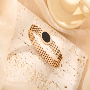 Rose gold honeycomb mesh bangle with black oval centerpiece on stone background